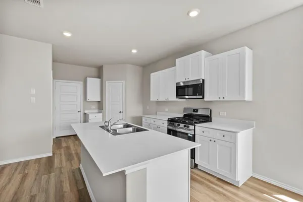 a kitchen that has a microwave a stove and white cabinets