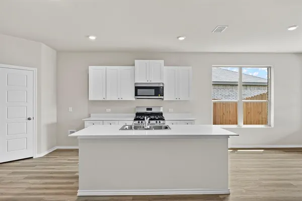 a kitchen with stainless steel appliances granite countertop a sink dishwasher a stove and a refrigerator with wooden floor