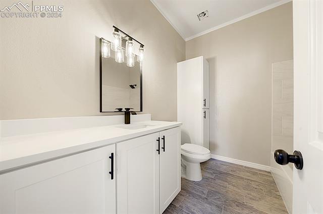 8160 Edison Road Yoder, CO 80864 - Photo 25 of 42 Bathroom with ornamental molding, toilet, large vanity, and hardwood / wood-style flooring