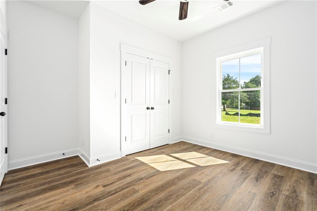 3216 South Phillips Road Lanett, AL 36863 - Photo 19 of 23 Wood-finish flooring, white paneled doors, ceiling fan, single-hung window, and white trim throughout