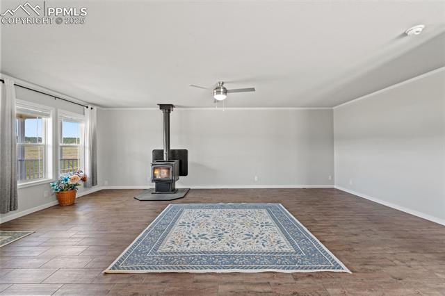 567 High Pasture Road Florissant, CO 80816 - Photo 4 of 48 Unfurnished living room featuring LVP floors, ceiling fan, and a wood stove