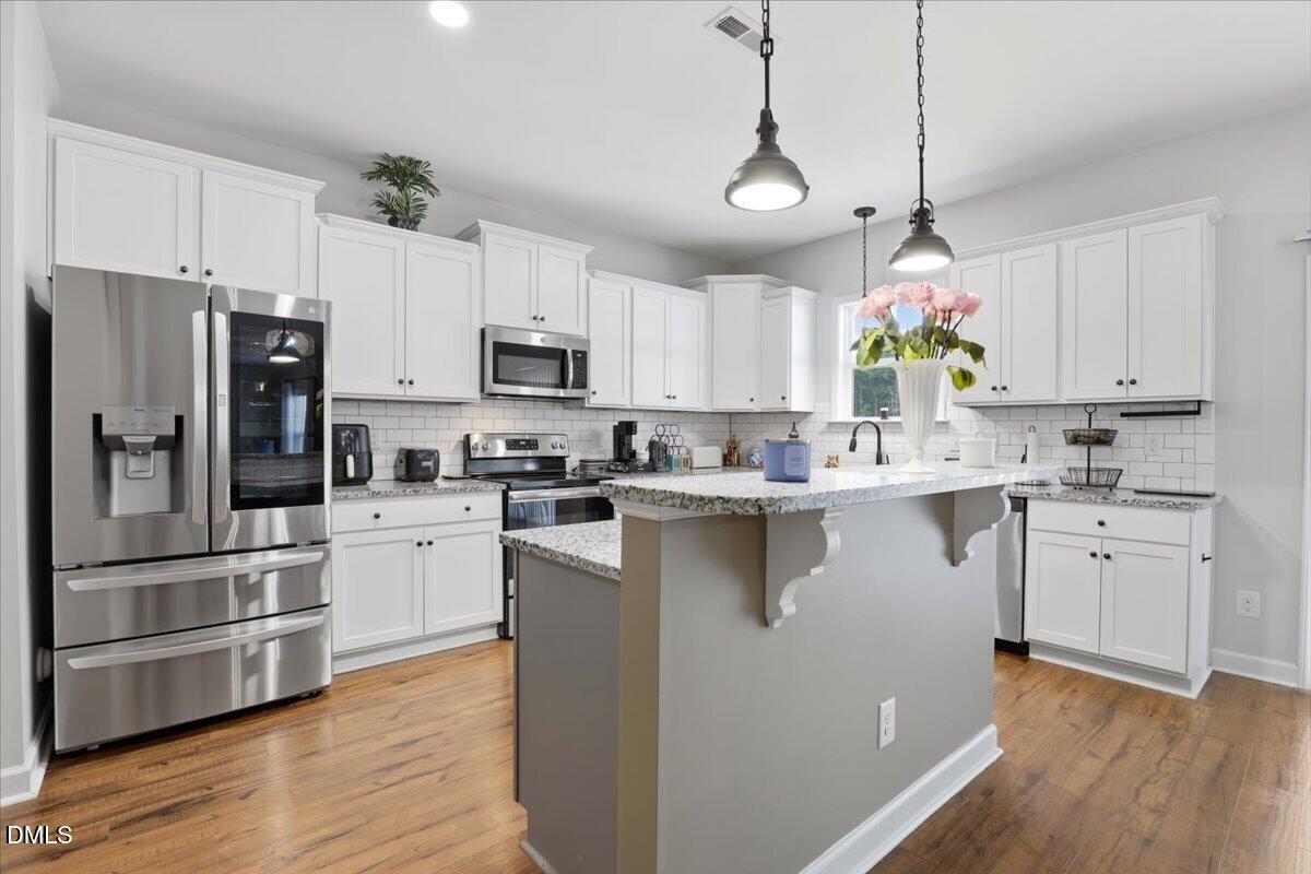 136 Fallingbrook Drive Kenly, NC 27542 - Photo 16 of 54 a kitchen with kitchen island white cabinets stainless steel appliances and wooden floor