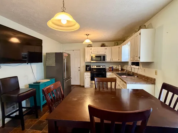 a kitchen with kitchen island granite countertop a dining table chairs stainless steel appliances and cabinets