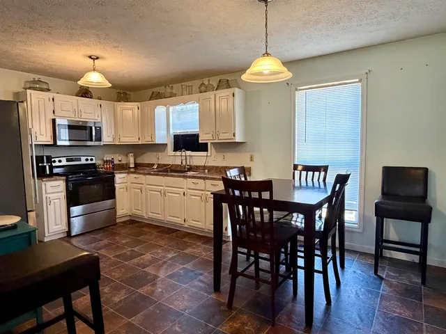 a kitchen with stainless steel appliances granite countertop a sink a stove a table and chairs