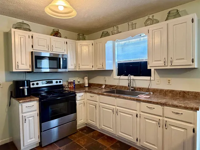 a kitchen with granite countertop white cabinets white stainless steel appliances and a sink