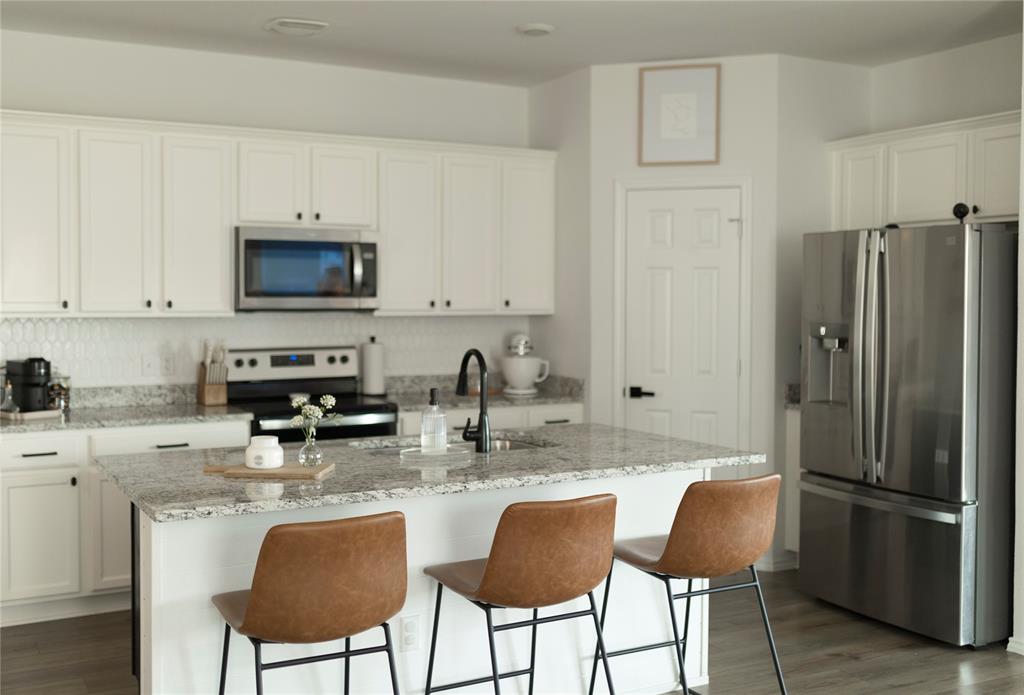 3224 Sherco Road Lorena, TX 76655 - Photo 7 of 20 a kitchen with stainless steel appliances granite countertop a stove a refrigerator a sink a stove a dining table and chairs with wooden floor