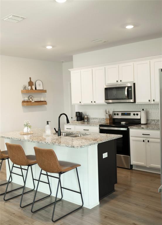 3224 Sherco Road Lorena, TX 76655 - Photo 9 of 20 a kitchen with granite countertop a stove top oven a sink dishwasher and white cabinets with wooden floor