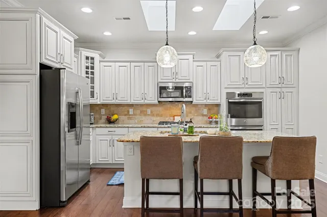 a kitchen with kitchen island granite countertop a center island a sink stainless steel appliances and cabinets