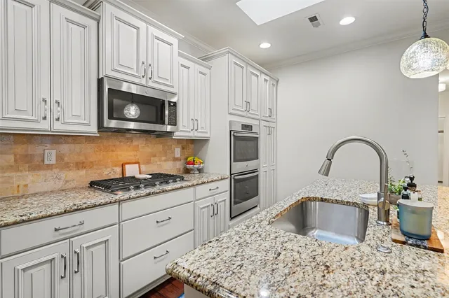 a kitchen with granite countertop a sink stainless steel appliances and white cabinets