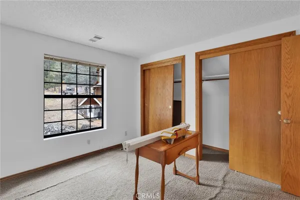 an empty room with windows and chandelier fan