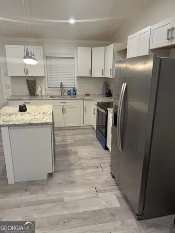 a kitchen with stainless steel appliances granite countertop a refrigerator a sink a stove and white cabinets