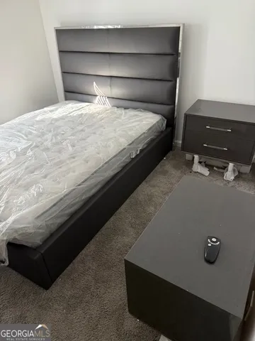 a bedroom with a bed and a lamp on dresser