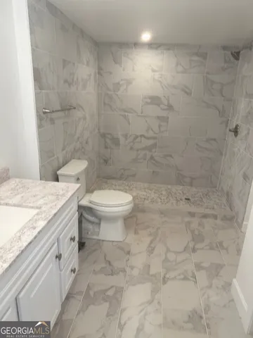 a bathroom with a granite countertop toilet a sink and a shower