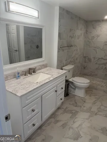 a bathroom with a granite countertop toilet sink and mirror