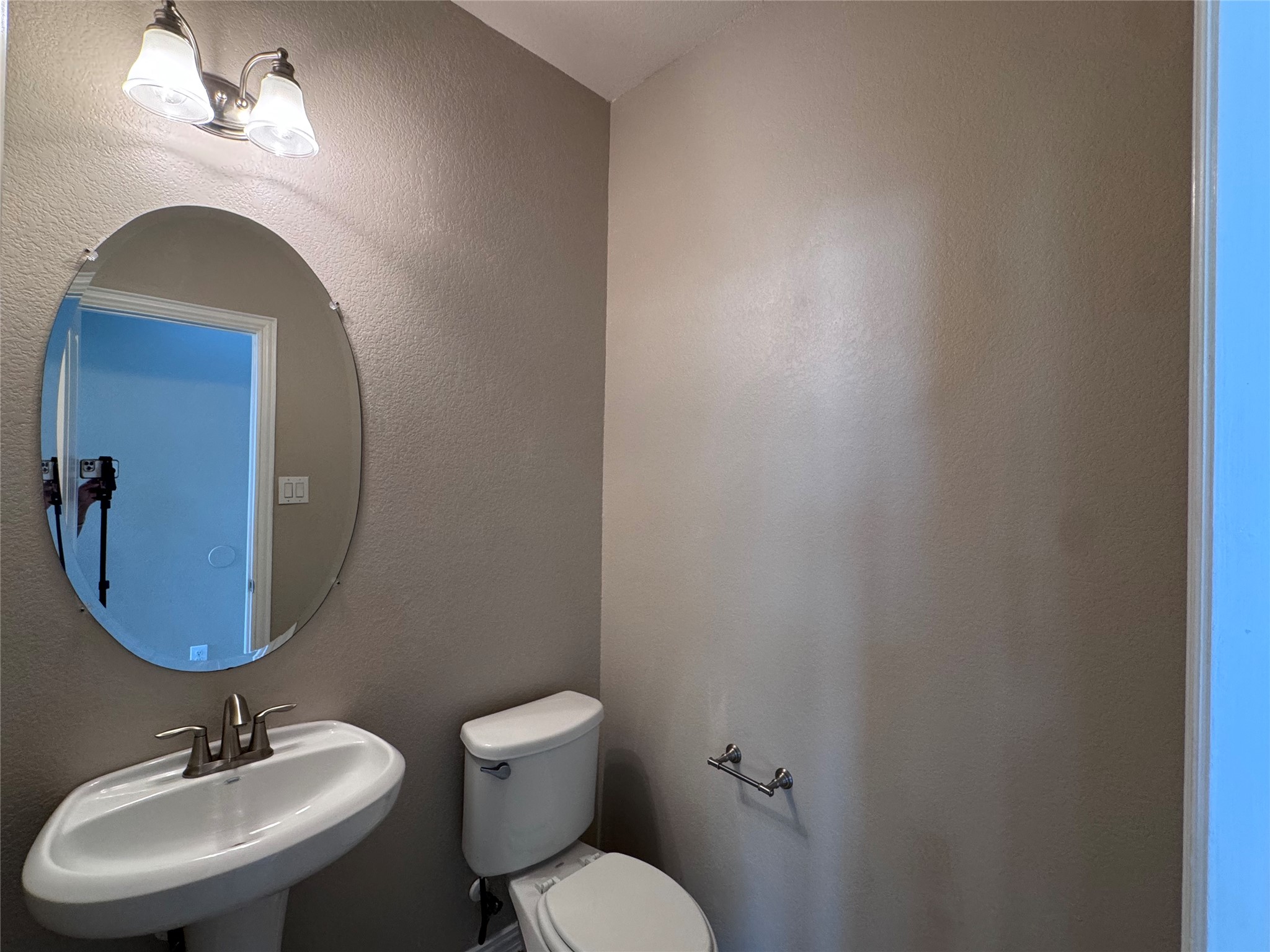 2605 Rough Berry Road Pflugerville, TX 78660 - Photo 16 of 40 A well-appointed powder room features a sleek pedestal sink and coordinating toilet, accented by a decorative wall mirror.