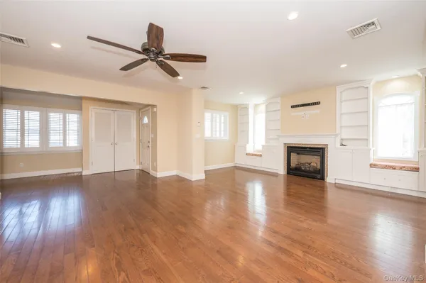 an empty room with wooden floor fireplace and windows