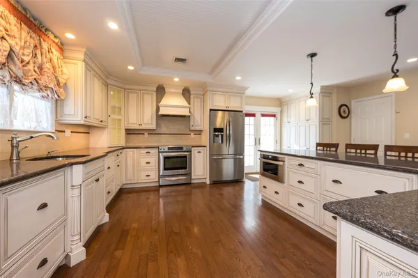 a large kitchen with stainless steel appliances granite countertop a lot of counter space and wooden floors