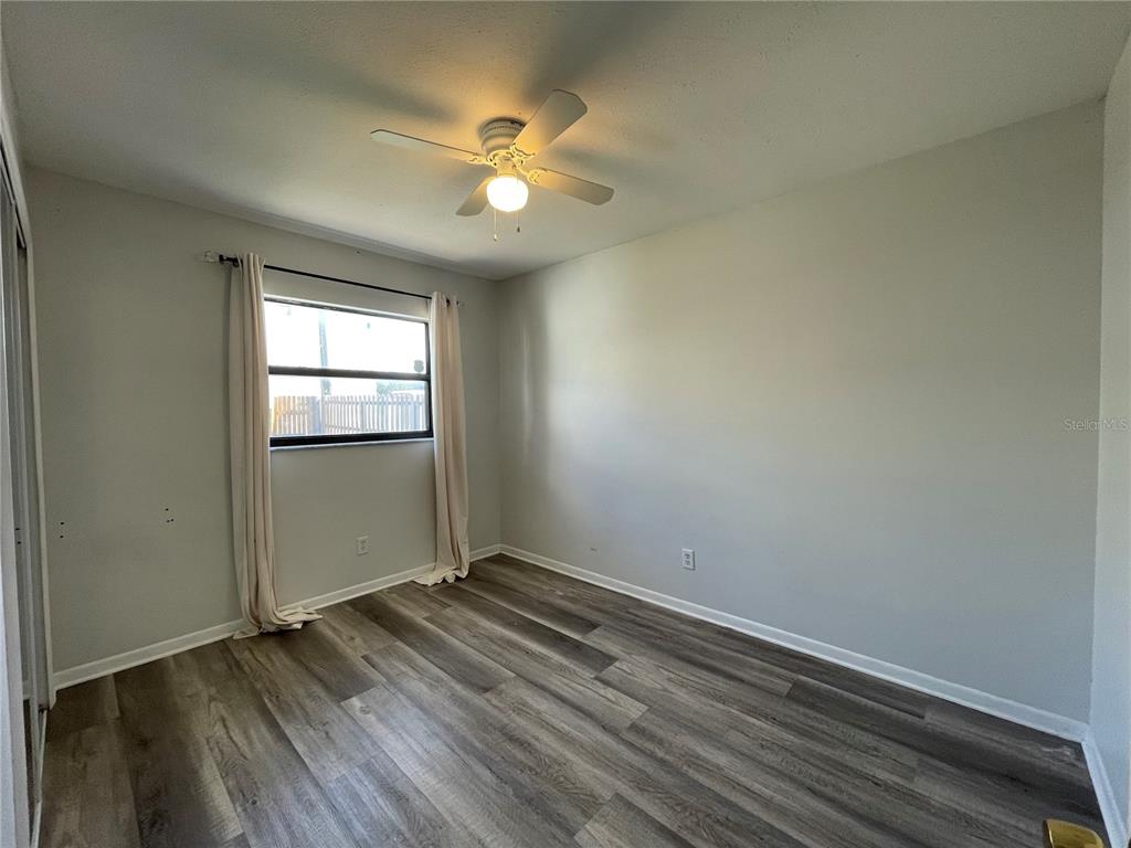 7199 121st Terrace Largo, FL 33773 - Photo 15 of 16 an empty room with wooden floor chandelier fan and windows