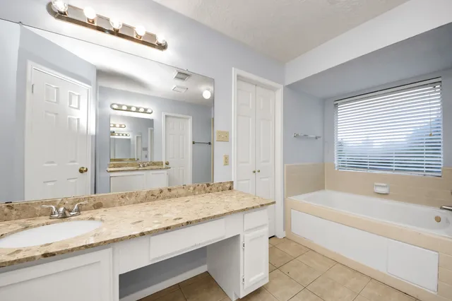 a bathroom with a granite countertop tub sink and mirror