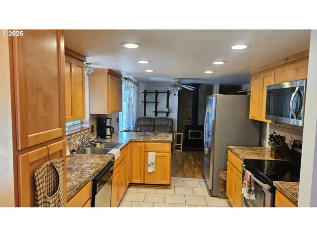 a kitchen with kitchen island granite countertop a sink counter top space appliances and cabinets