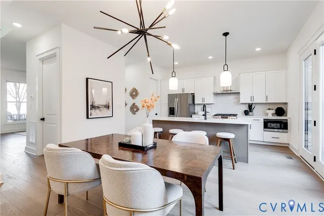 a kitchen with stainless steel appliances granite countertop a sink a stove a refrigerator and island with wooden floor