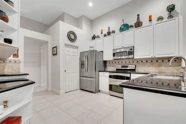 a kitchen with stainless steel appliances granite countertop a refrigerator and a stove top oven
