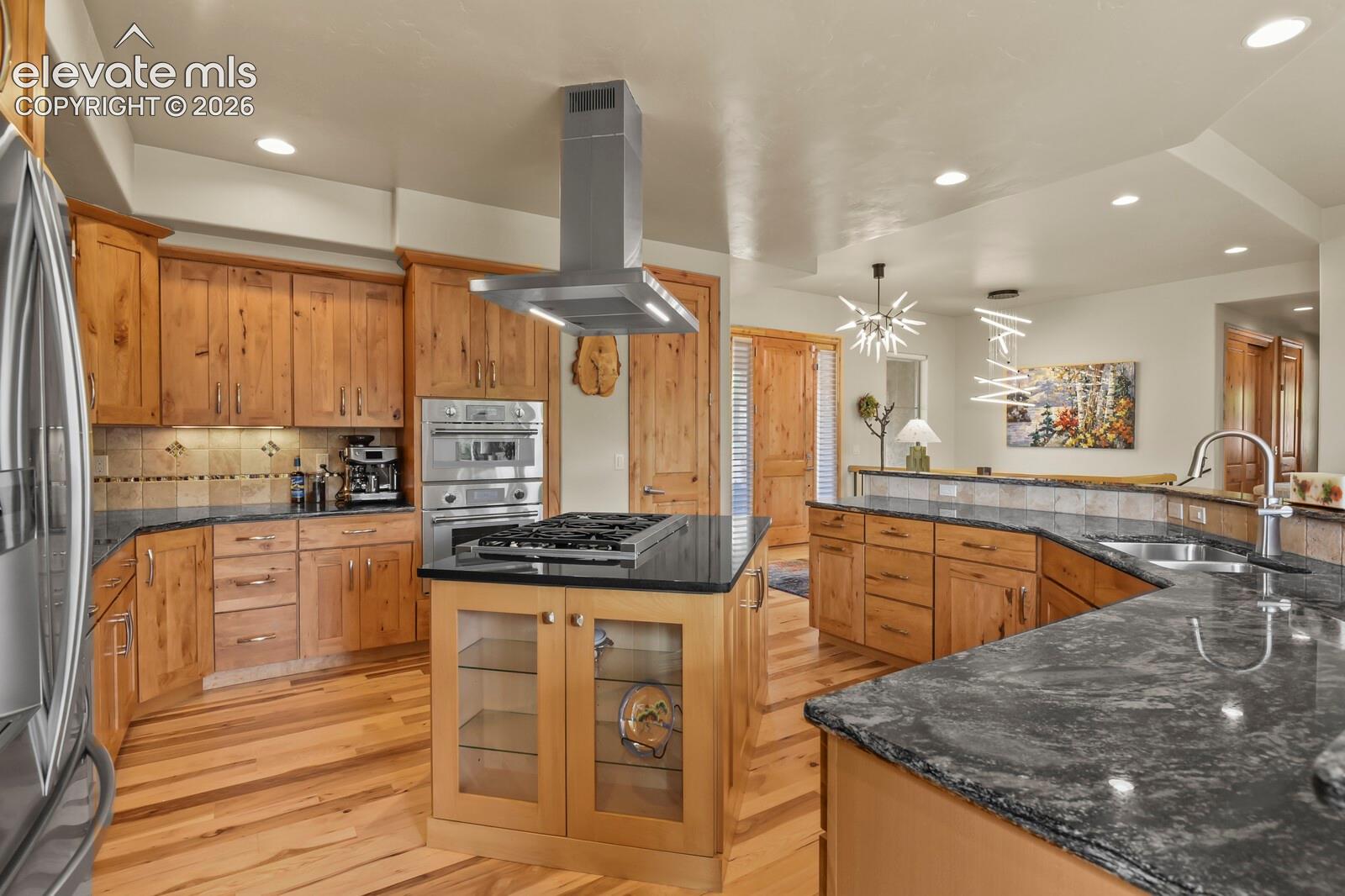 5545 Wilson Road Colorado Springs, CO 80919 - Photo 11 of 48 Gourmet kitchen featuring wood-finish cabinetry, dark stone countertops, stainless steel appliances.