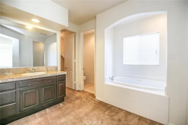 a spacious bathroom with a tub sink and mirror