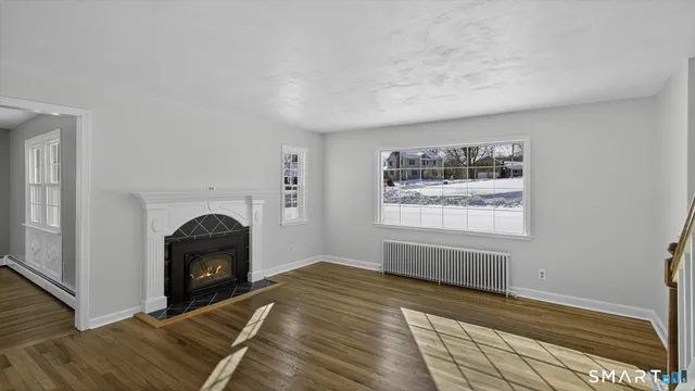 a view of empty room with fireplace and wooden floor