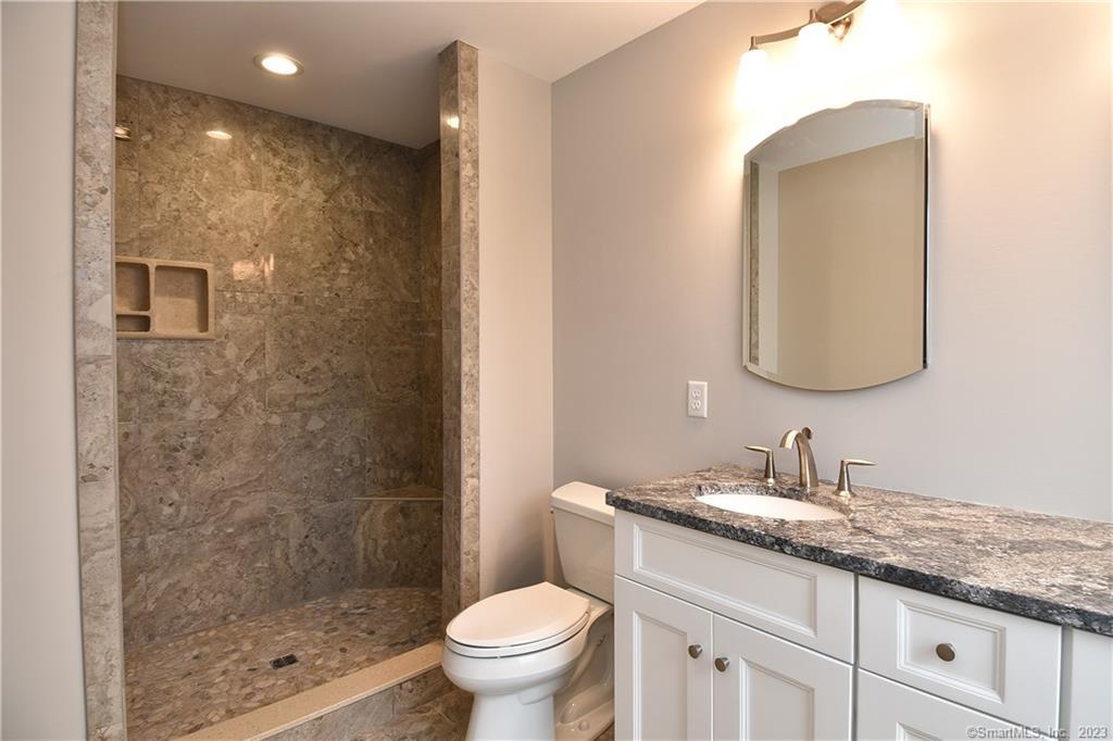 46 Village Crossing, Unit 46 Niantic, CT 06357 - Photo 15 of 24 a bathroom with a granite countertop sink a toilet and a mirror