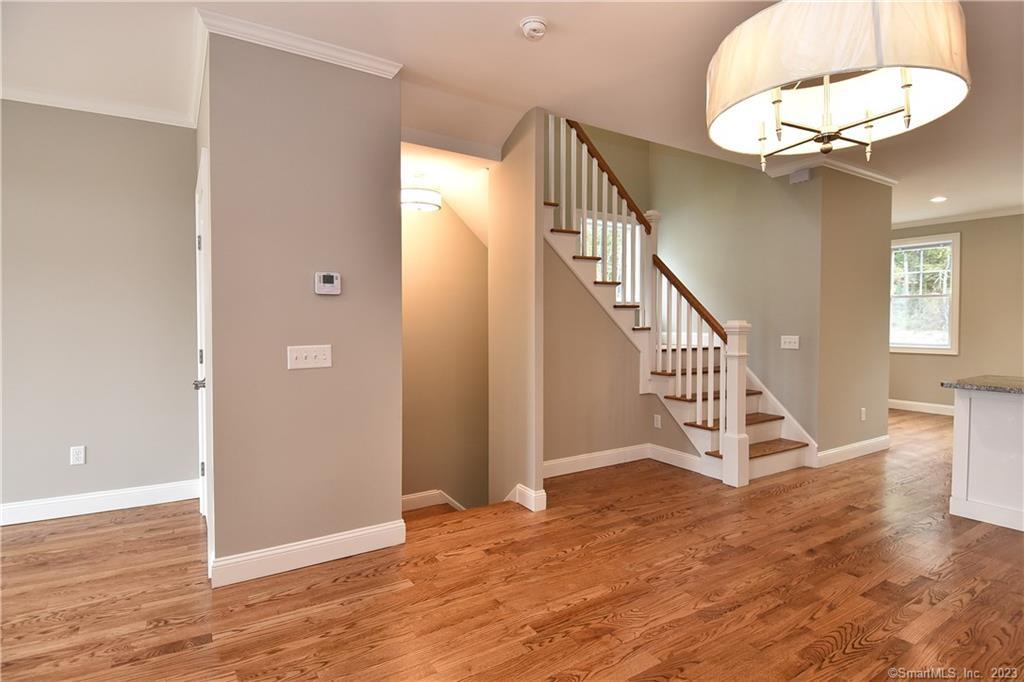 46 Village Crossing, Unit 46 Niantic, CT 06357 - Photo 10 of 24 wooden floor in an empty room with a chandelier fan and wooden floor