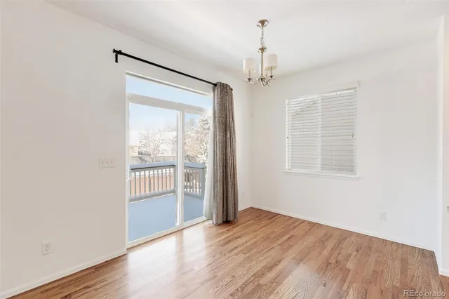 an empty room with wooden floor a ceiling fan and windows