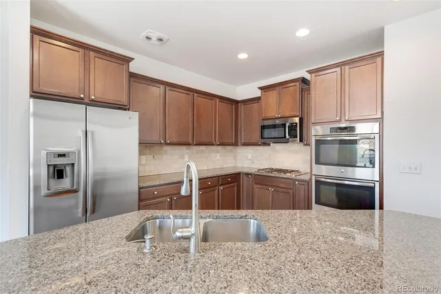 a kitchen with granite countertop a refrigerator stove and oven