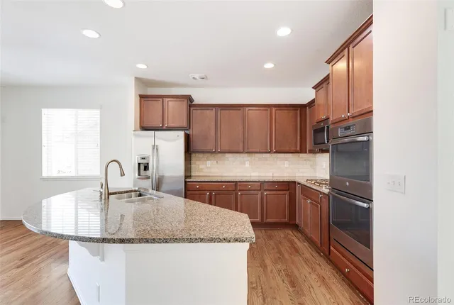 a kitchen with kitchen island granite countertop a sink stainless steel appliances and cabinets