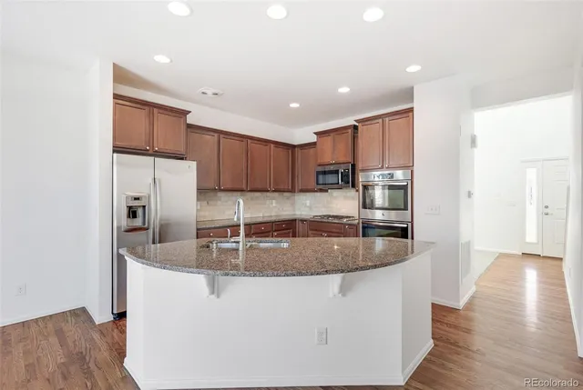 a kitchen with stainless steel appliances granite countertop a sink a refrigerator and a granite counter tops