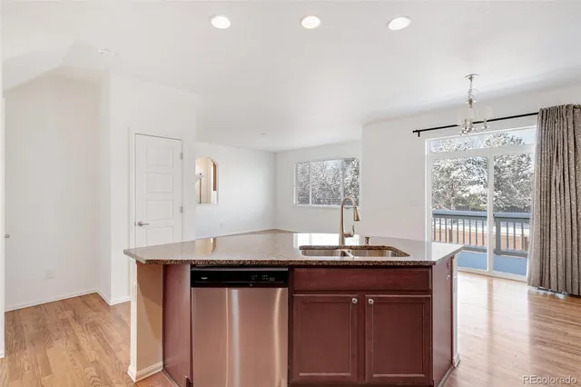 a kitchen with kitchen island granite countertop a sink cabinets and wooden floor