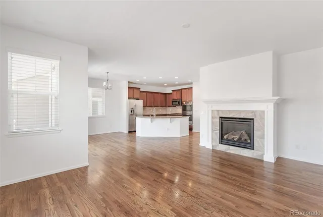 a view of a big room with wooden floor and a kitchen
