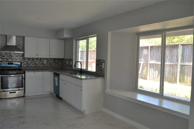 a kitchen with granite countertop a stove a sink and a refrigerator