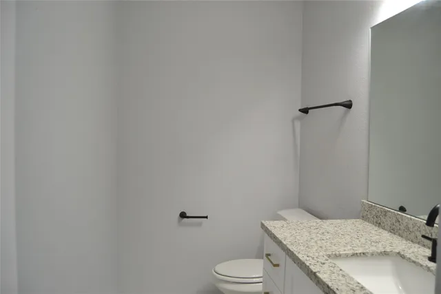 a bathroom with a granite countertop sink a toilet and vanity