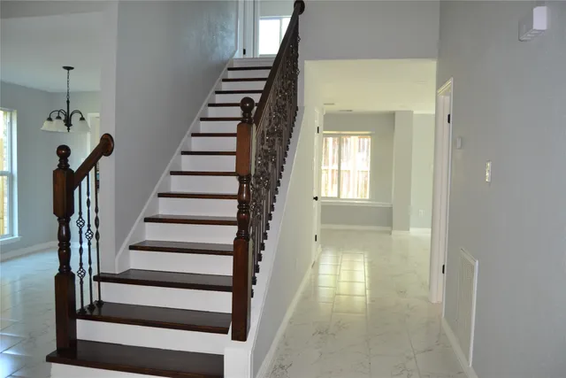 a view of a hallway with stairs and wooden floor