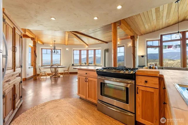 a kitchen with stainless steel appliances granite countertop a stove and a view of living room