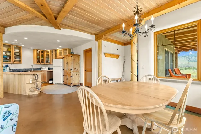 a dining hall with stainless steel appliances kitchen island granite countertop a table chairs and a chandelier