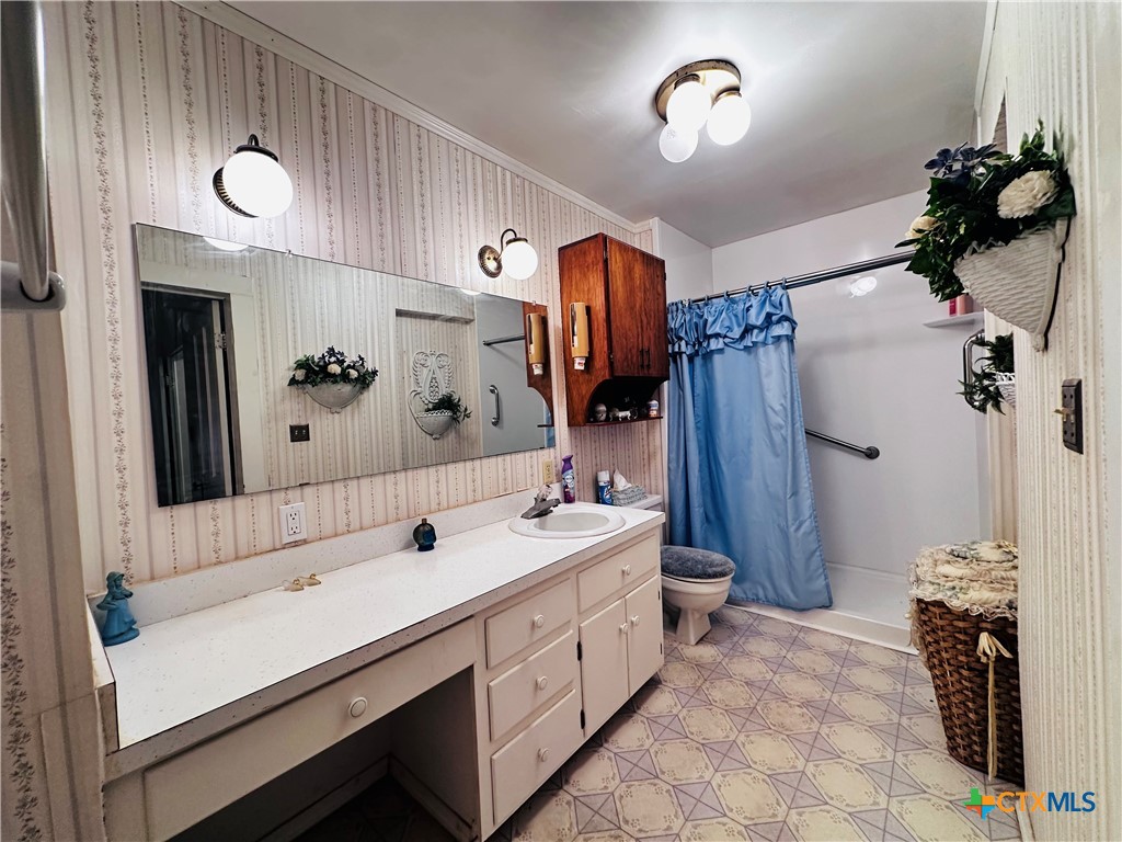 608 Coke Street Yoakum, TX 77995 - Photo 10 of 22 a bathroom with a double vanity sink a toilet and a mirror