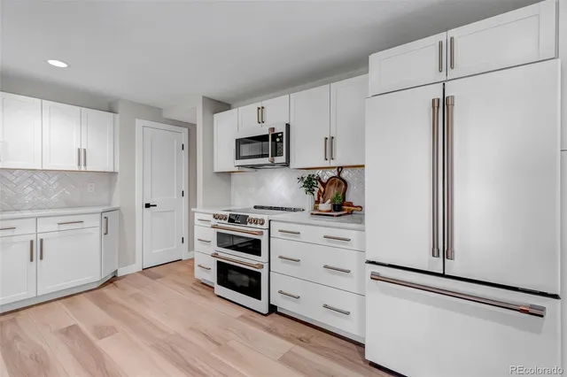 a kitchen with stainless steel appliances white cabinets and a refrigerator