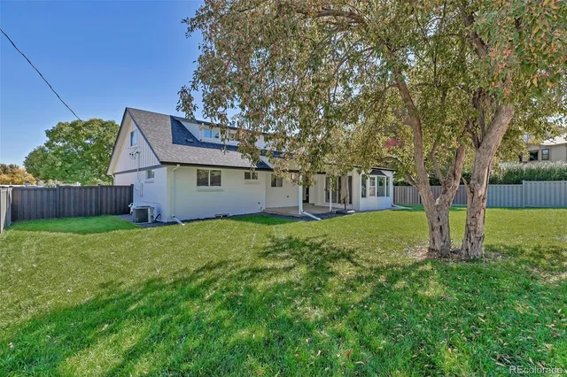 a view of a house with backyard and a tree