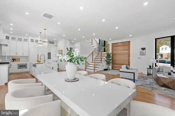 a large kitchen with granite countertop a dining table chairs and white cabinets