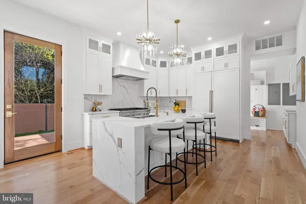 a kitchen with stainless steel appliances kitchen island granite countertop a stove a sink dishwasher and white cabinets with wooden floor