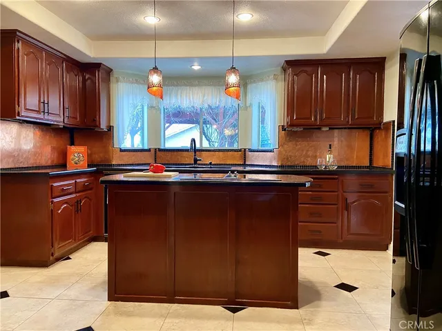 a kitchen with kitchen island granite countertop a sink appliances cabinets and a counter top space