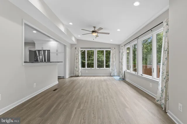 a view of an empty room with a window and wooden floor