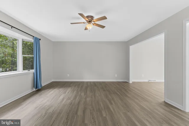 an empty room with windows and fan
